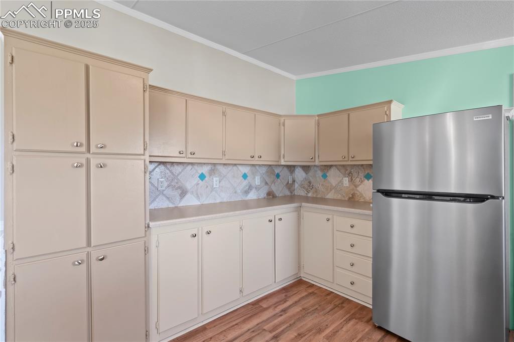 Image 7 of 29: Kitchen featuring freestanding refrigerator, cream cabinetry, light counter