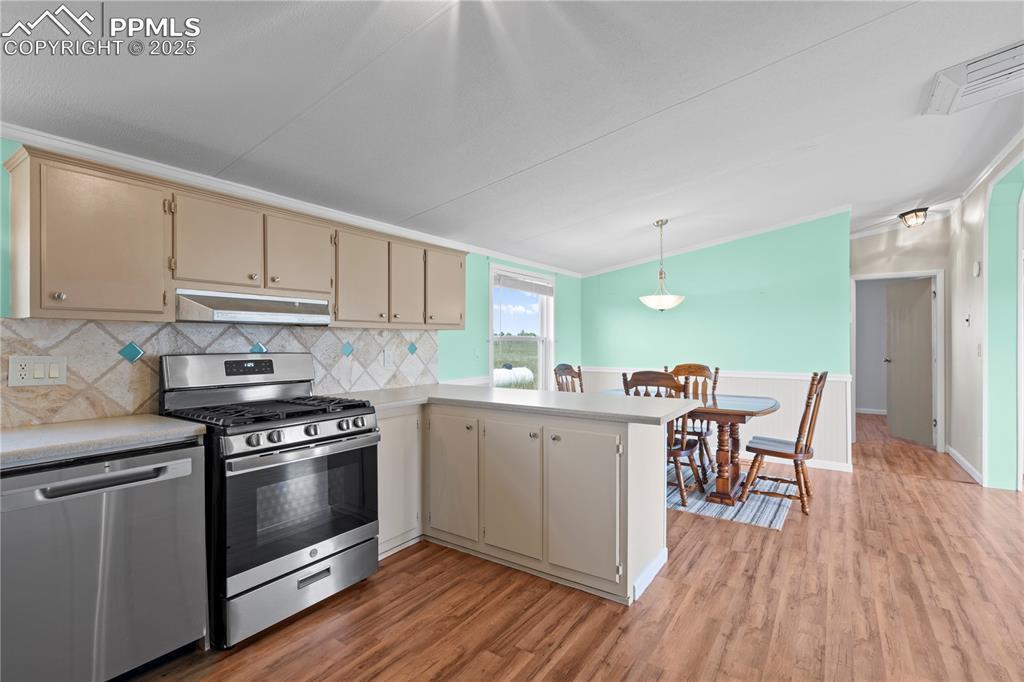 Image 8 of 29: Kitchen featuring stainless steel appliances, a peninsula, backsplash, ligh