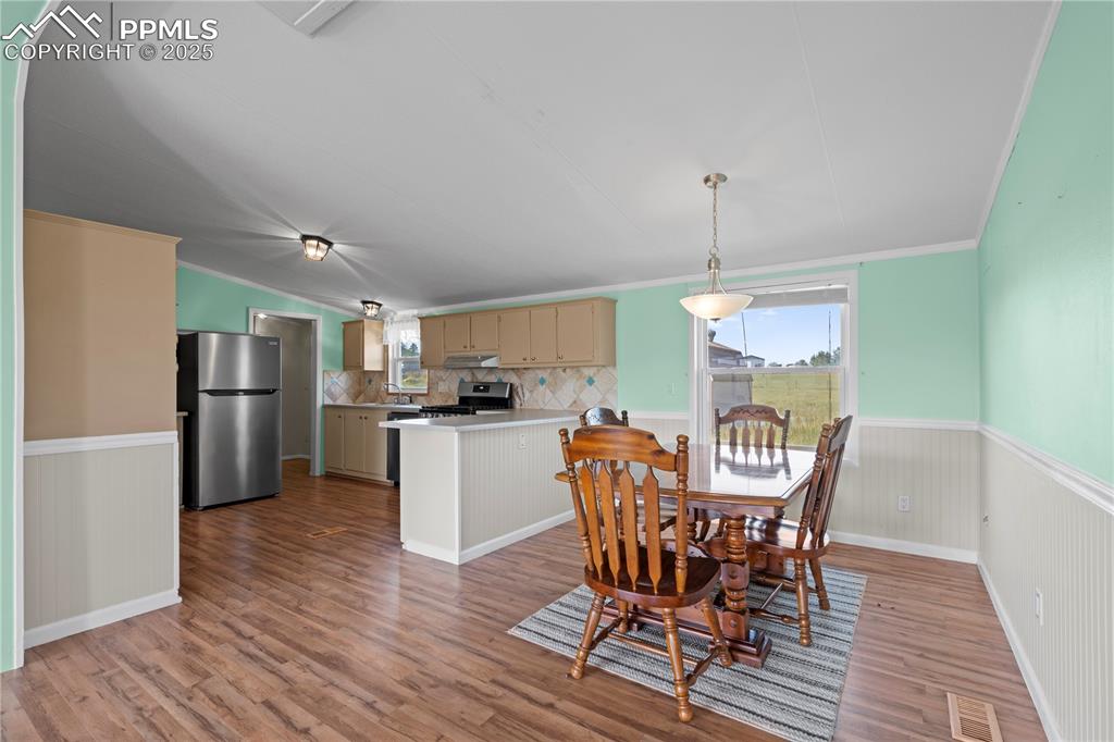 Image 9 of 29: Dining room with a wainscoted wall, crown molding, light wood-style floorin