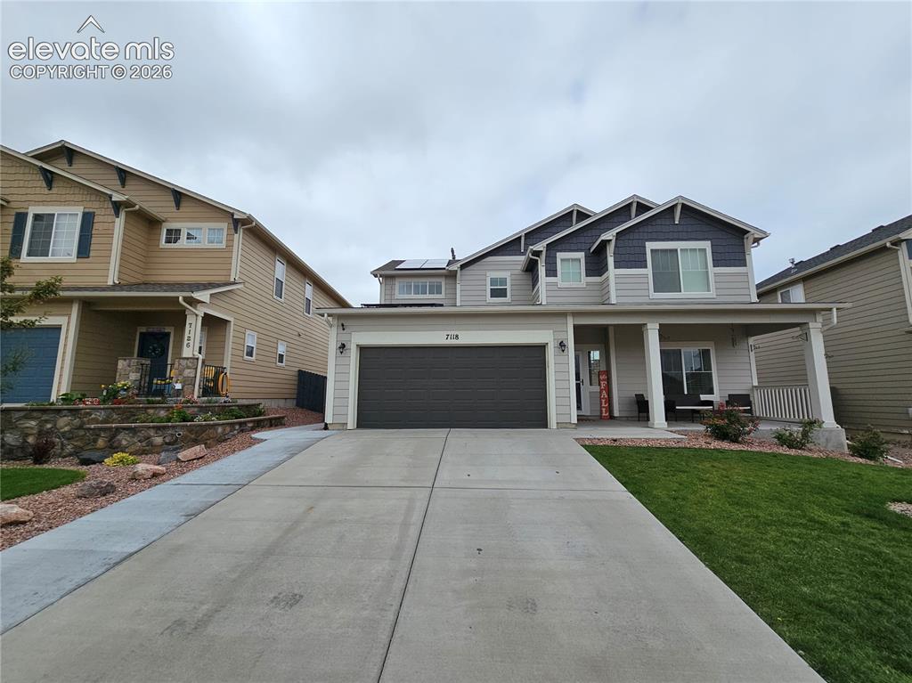 Caption: Contemporary two-story residence featuring a covered front porch, dual-pane windows, and an attached
