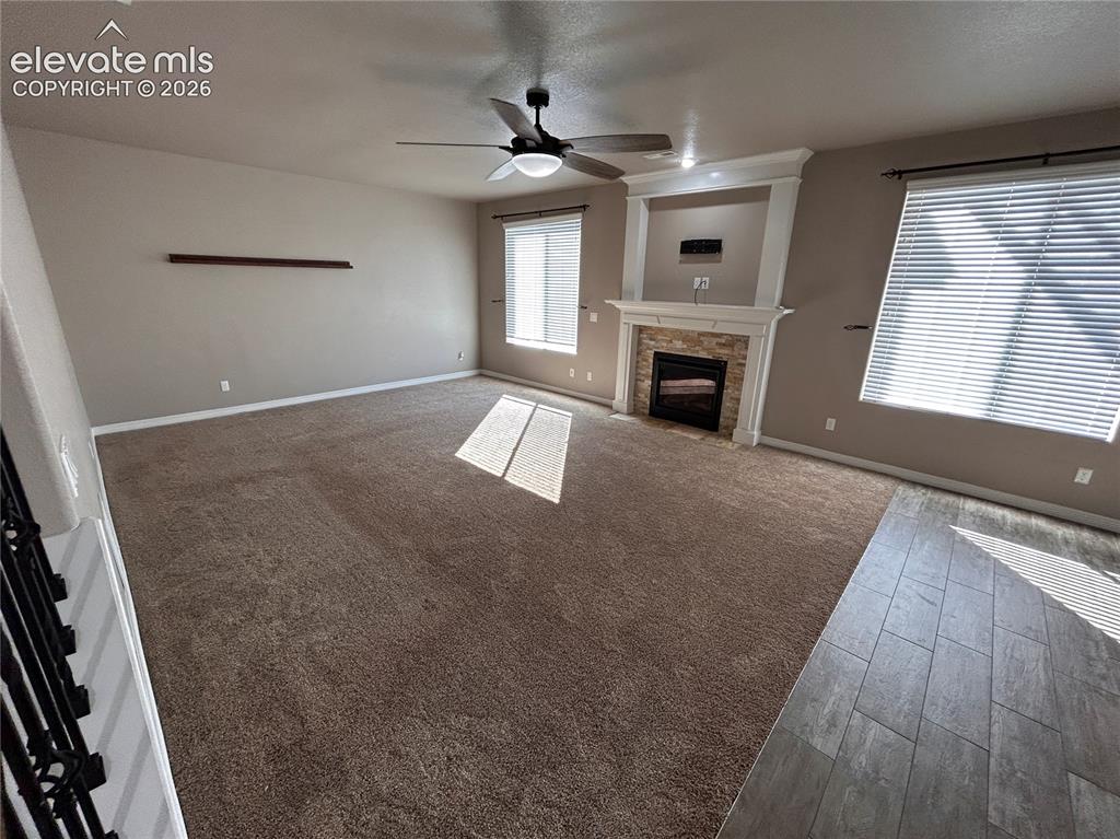 Image 10 of 24: Spacious living area featuring a stone-faced fireplace with white mantel, t