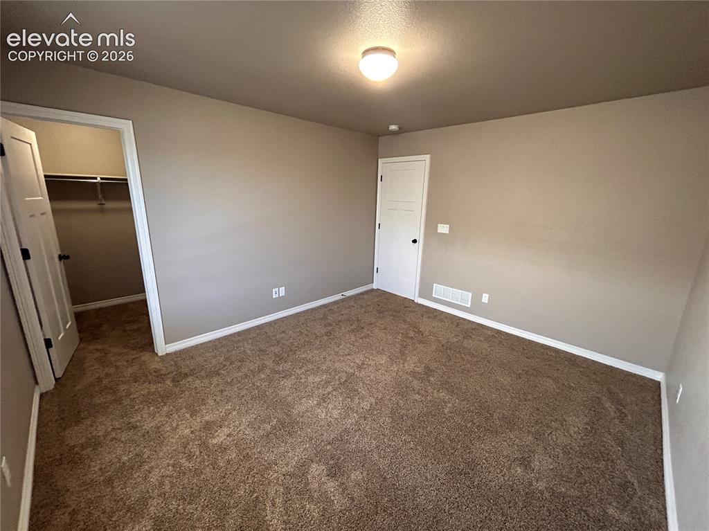 Image 14 of 24: Neutral-toned bedroom with textured brown carpeting and a flush-mount ceili