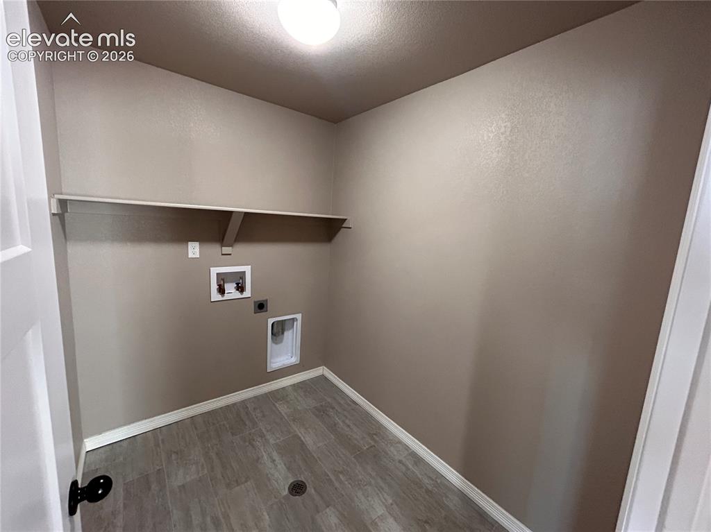 Image 15 of 24: Dedicated laundry space featuring a built-in shelf, neutral wall tones, whi