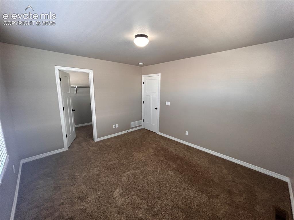Image 17 of 24: Spacious room featuring neutral paint, brown carpet, and white trim