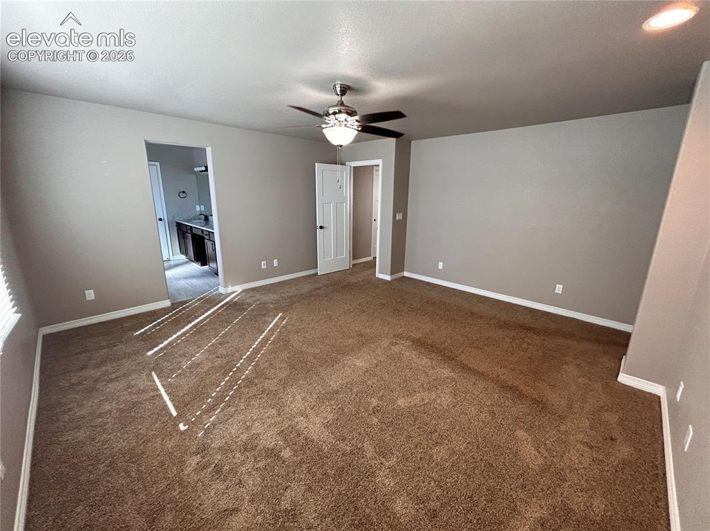 Image 20 of 24: Spacious room featuring brown carpet, light gray wall paint, and white base
