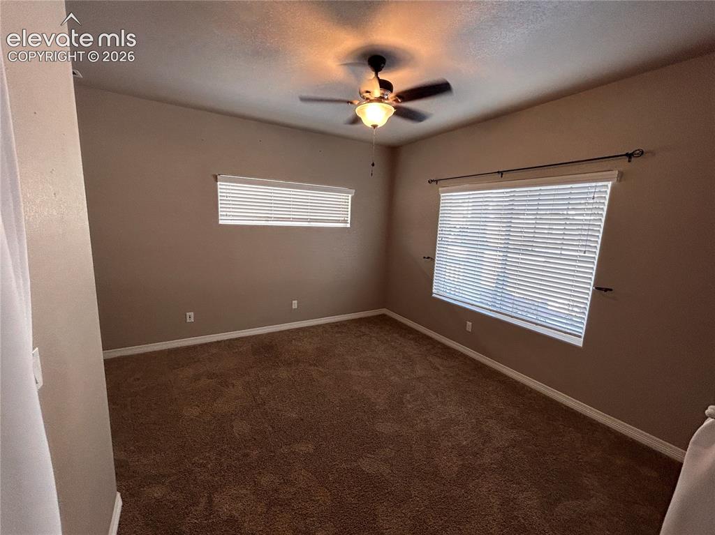 Image 3 of 24: Carpeted room featuring a ceiling fan with integrated lighting, two windows