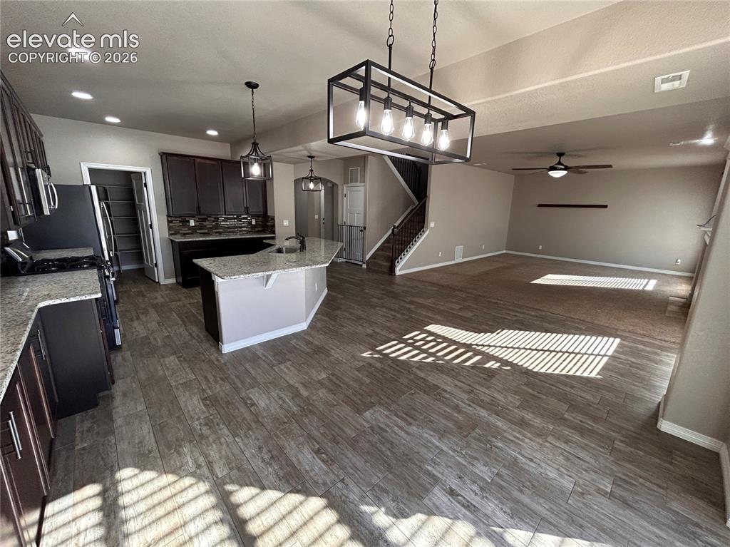 Image 6 of 24: Spacious open-concept living area featuring wood-finish flooring, a kitchen