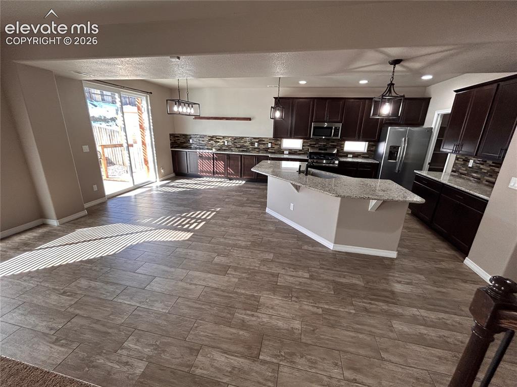 Image 7 of 24: Open-concept kitchen and living area featuring wood-finish tile flooring