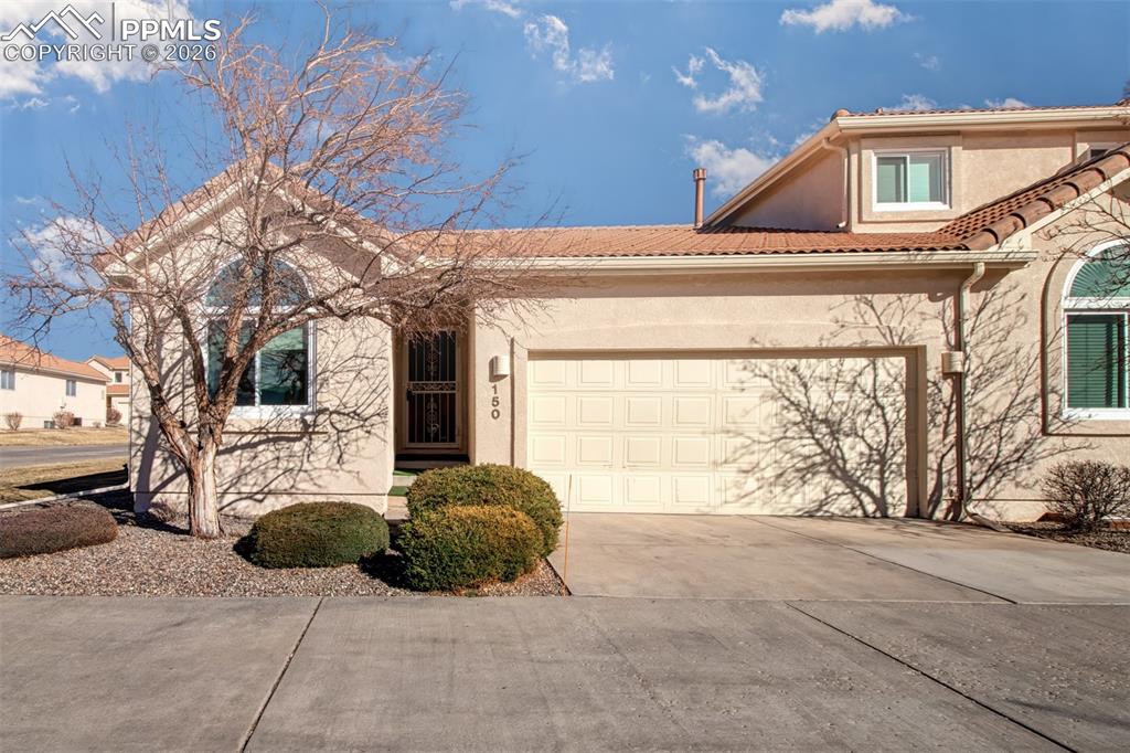 Image 1 of 30: Low-maintenance end unit townhome with stucco exterior and inviting covered