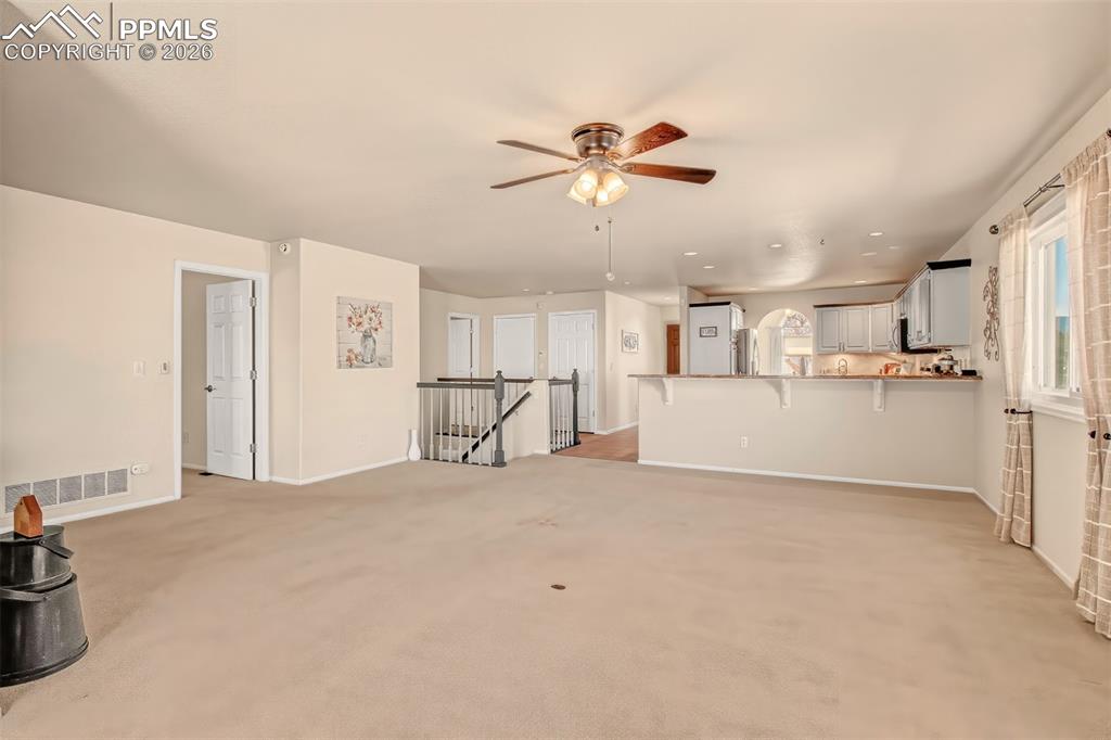 Image 10 of 30: Living room adjacent to the kitchen, complete with extra bar seating.
