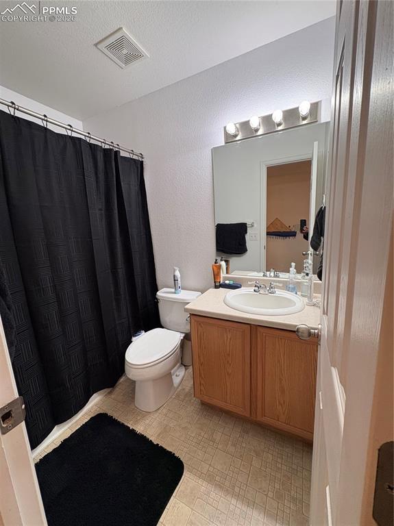 Image 16 of 21: Bathroom featuring vanity, curtained shower, and a textured wall