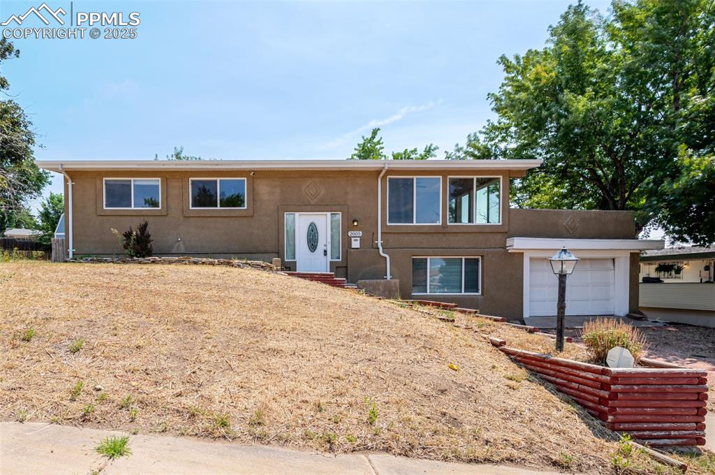 Caption: View of front facade featuring a garage and stucco siding