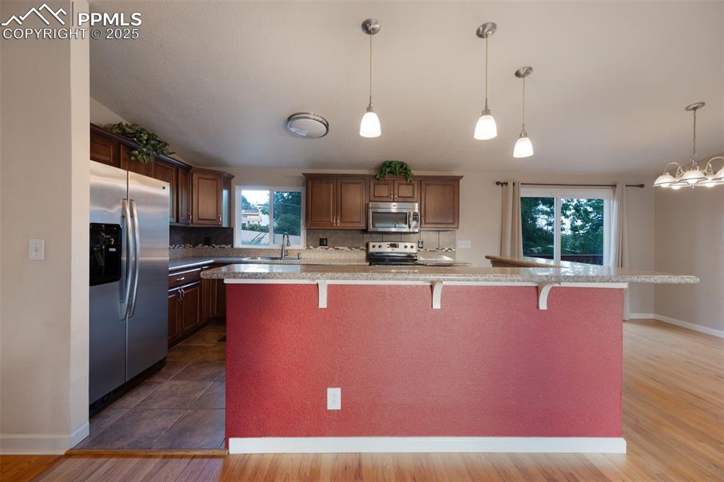 Image 12 of 43: Kitchen featuring stainless steel appliances, hanging light fixtures, a bre