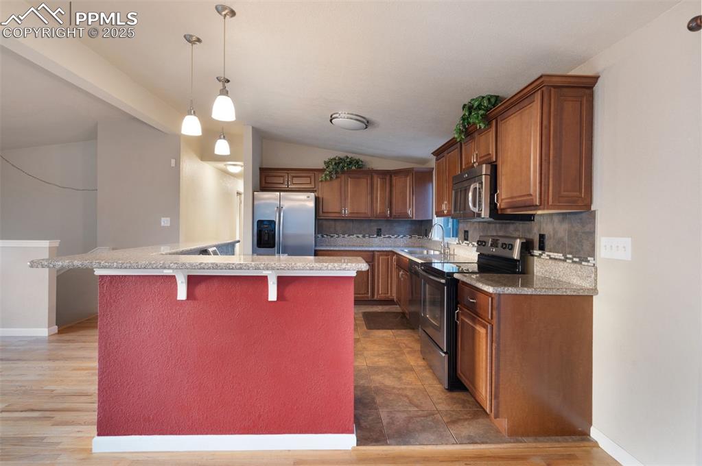 Image 15 of 43: Kitchen with decorative light fixtures, appliances with stainless steel fin