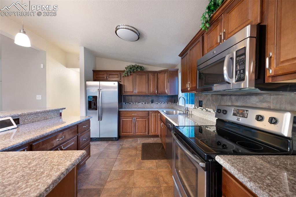 Image 16 of 43: Kitchen featuring appliances with stainless steel finishes, lofted ceiling,
