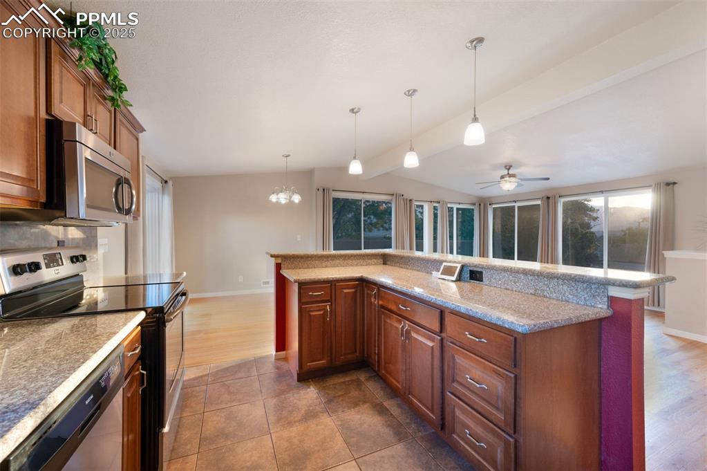 Image 17 of 43: Kitchen featuring stainless steel appliances, brown cabinets, hanging light