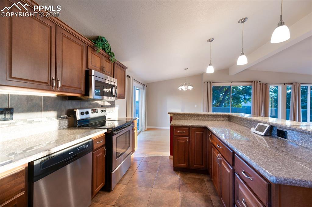 Image 18 of 43: Kitchen with appliances with stainless steel finishes, pendant lighting, a 