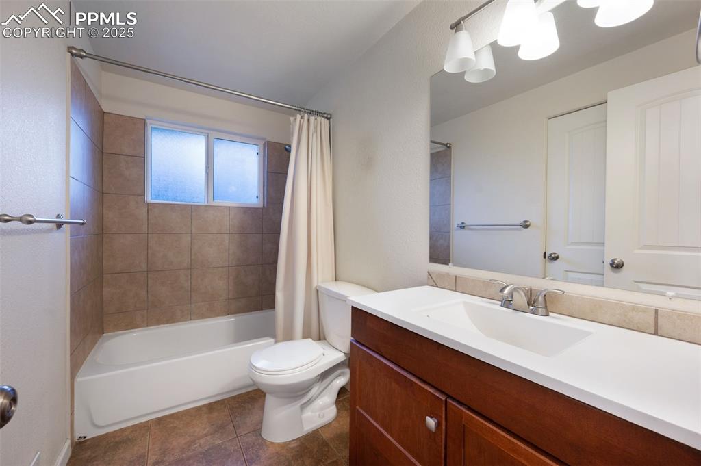 Image 24 of 43: Bathroom with shower / bath combo with shower curtain, vanity, and dark til