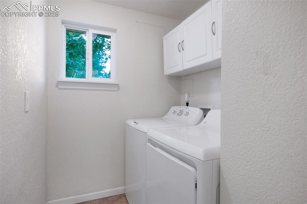 Image 27 of 43: Laundry area featuring a textured wall, cabinet space, and washing machine 
