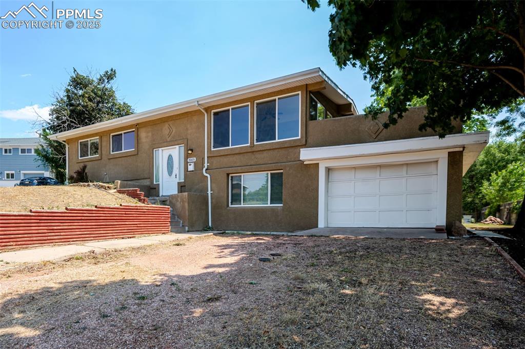 Image 3 of 43: View of front of home with an attached garage, stucco siding, and driveway