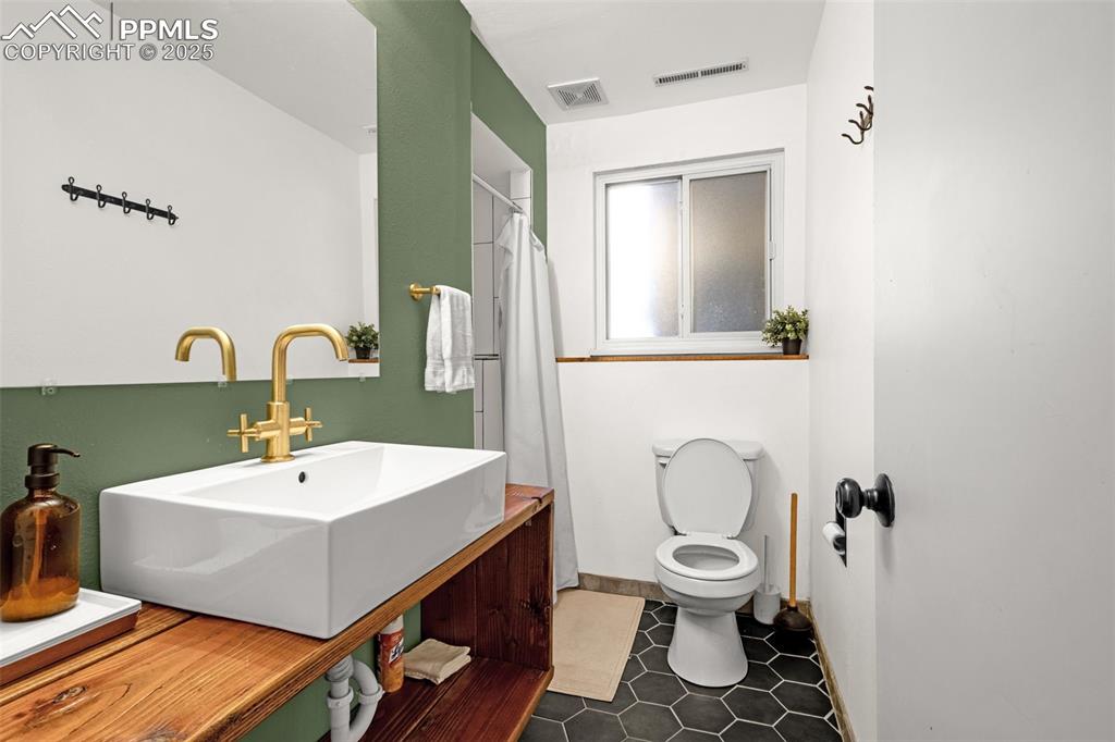 Image 19 of 32: Full bathroom with vanity, tile patterned flooring, and a shower with showe