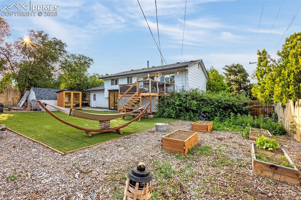 Image 5 of 32: Rear view of property featuring a garden, a fenced backyard, a wooden deck,