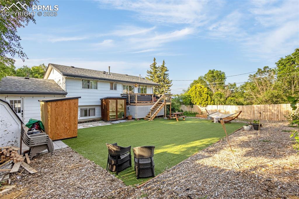 Image 6 of 32: Back of house featuring a deck, a fenced backyard, stairs, and a storage sh