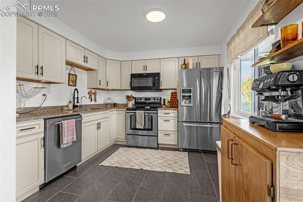Image 9 of 32: Kitchen featuring appliances with stainless steel finishes, light stone cou