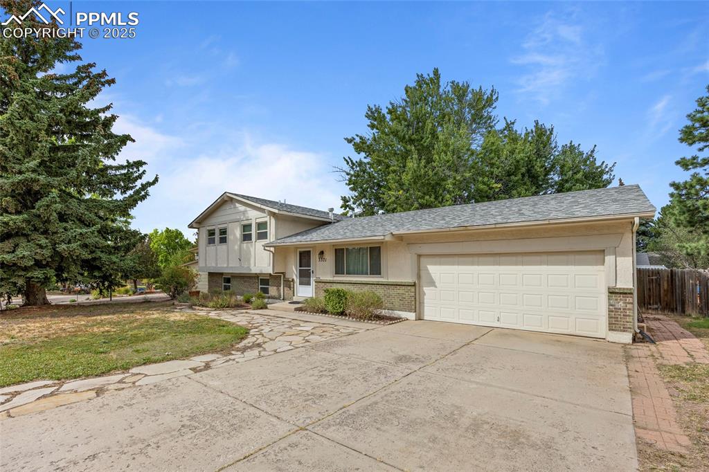Image 16 of 50: Split level home featuring brick siding, concrete driveway, an attached gar
