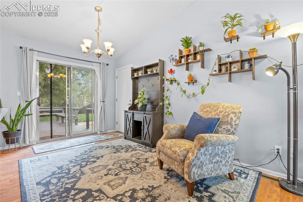 Image 19 of 50: Living area with wood finished floors, lofted ceiling, and a chandelier
