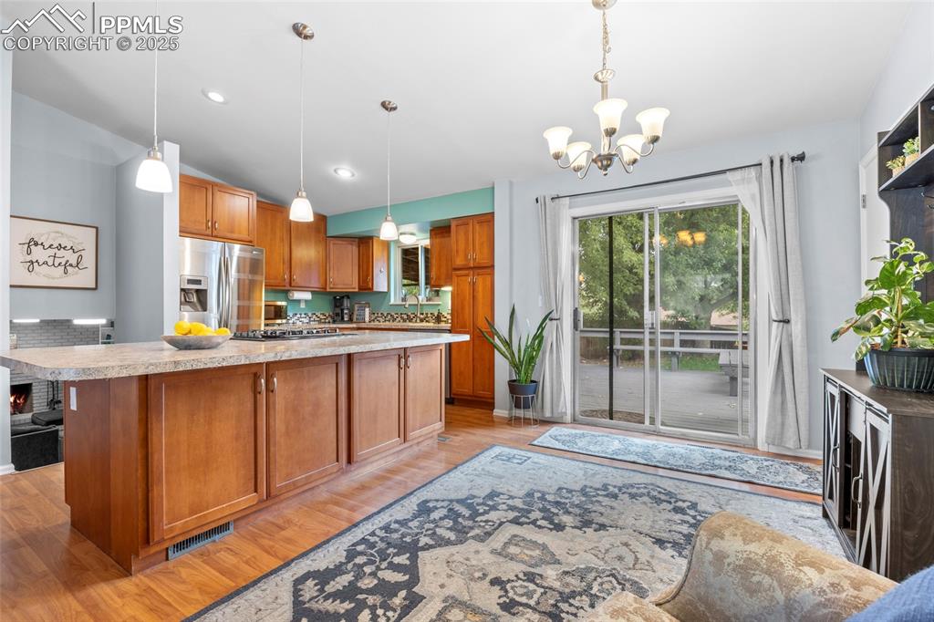 Image 20 of 50: Kitchen with brown cabinets, light wood finished floors, light countertops,