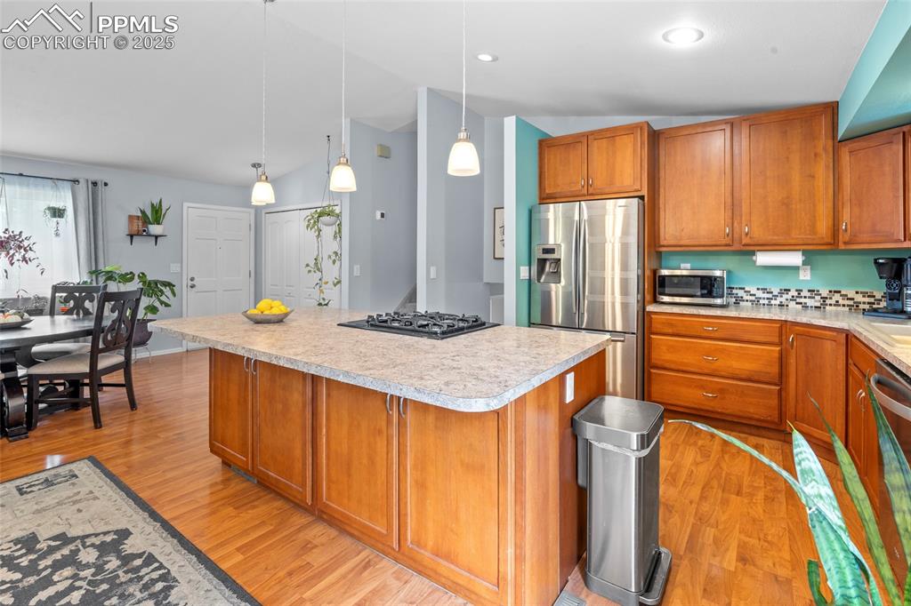 Image 21 of 50: Kitchen with brown cabinets, light wood finished floors, stainless steel ap