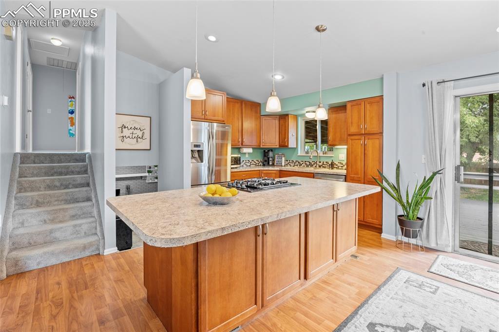 Image 23 of 50: Kitchen featuring light countertops, light wood-style floors, hanging light