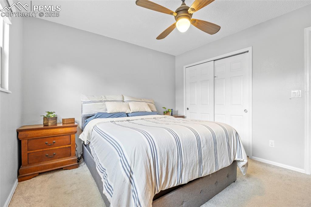 Image 28 of 50: Bedroom featuring light carpet, a ceiling fan, and a closet