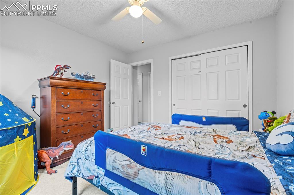 Image 30 of 50: Carpeted bedroom with a closet, a textured ceiling, and a ceiling fan