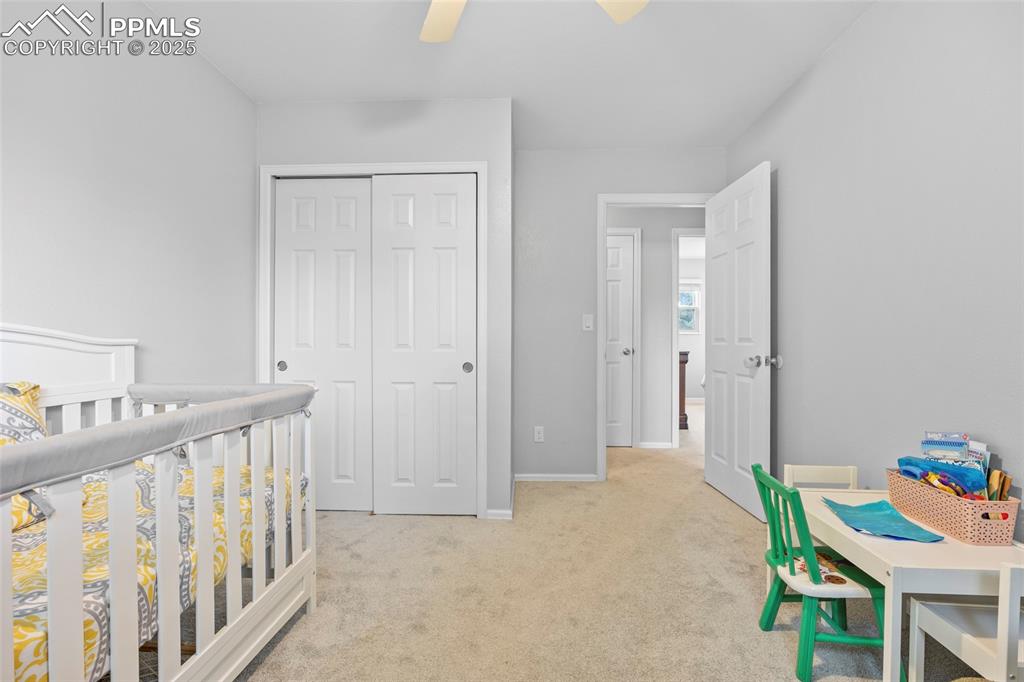 Image 31 of 50: Bedroom with light carpet, a closet, a ceiling fan, and a nursery area