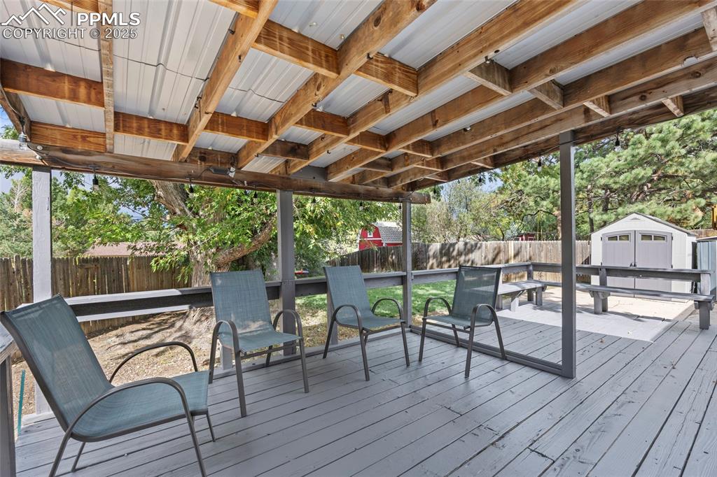 Image 36 of 50: Wooden terrace with a fenced backyard and a shed