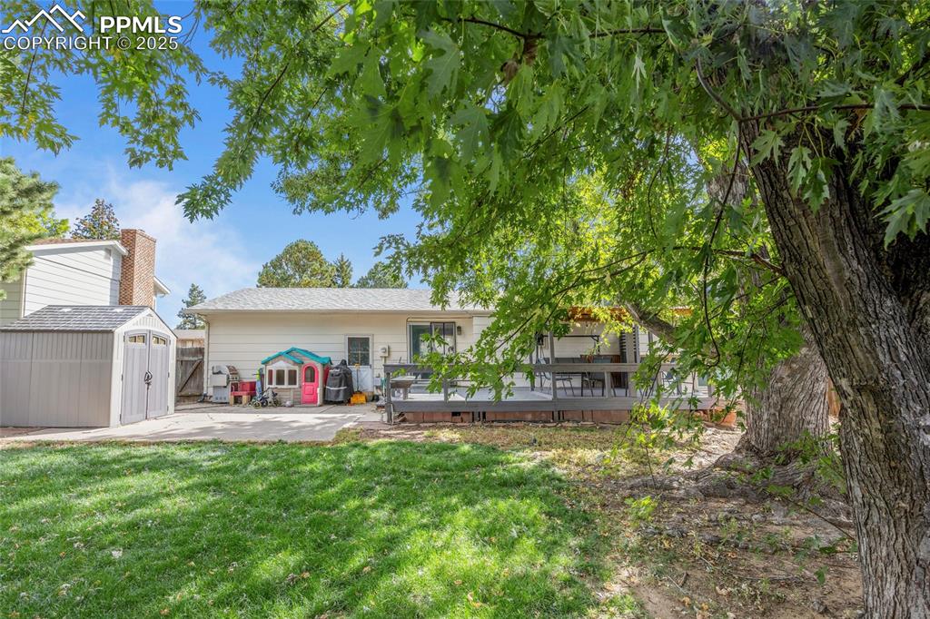 Image 39 of 50: Rear view of house with a wooden deck, a storage shed, and a yard