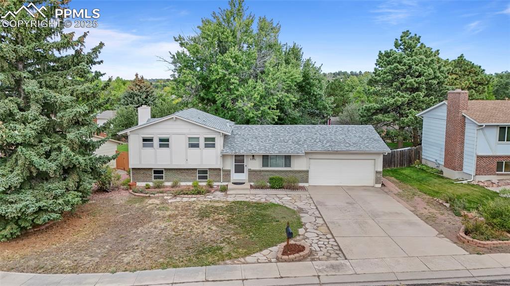 Image 47 of 50: Tri-level home featuring brick siding, driveway, an attached garage, a shin