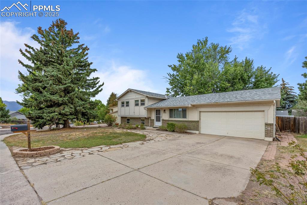 Image 48 of 50: Tri-level home featuring driveway, a garage, brick siding, and roof with sh