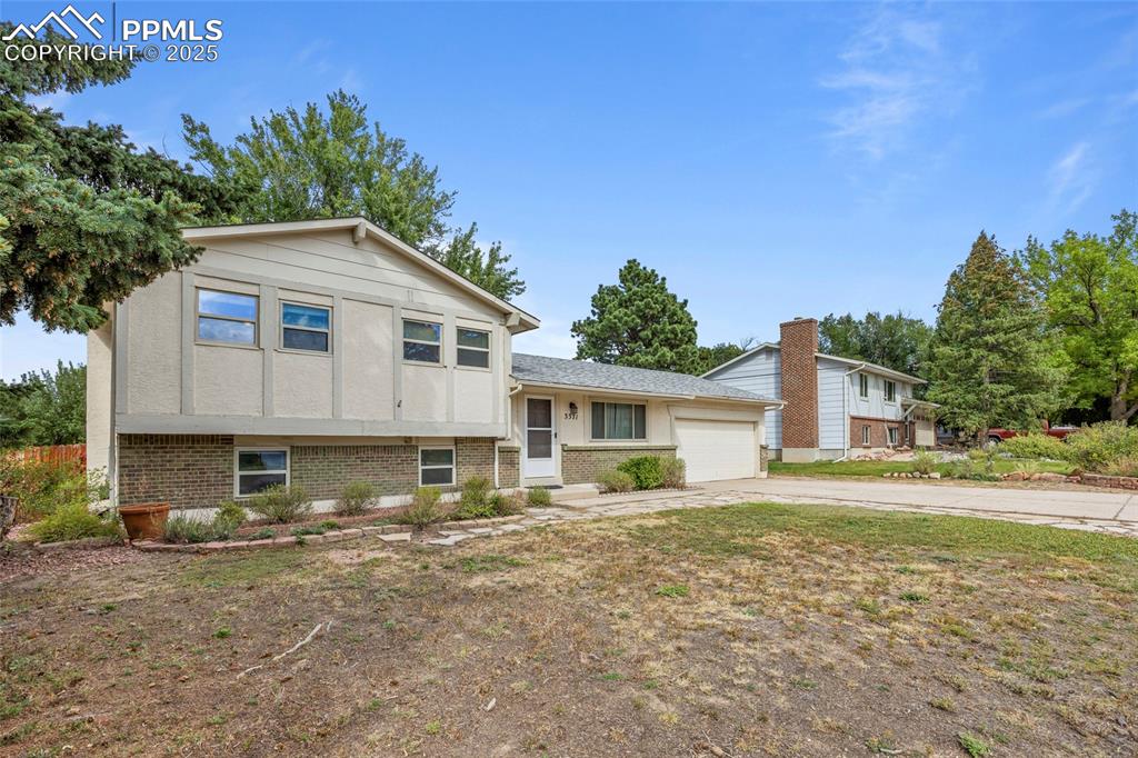 Image 50 of 50: Tri-level home featuring brick siding, an attached garage, and concrete dri