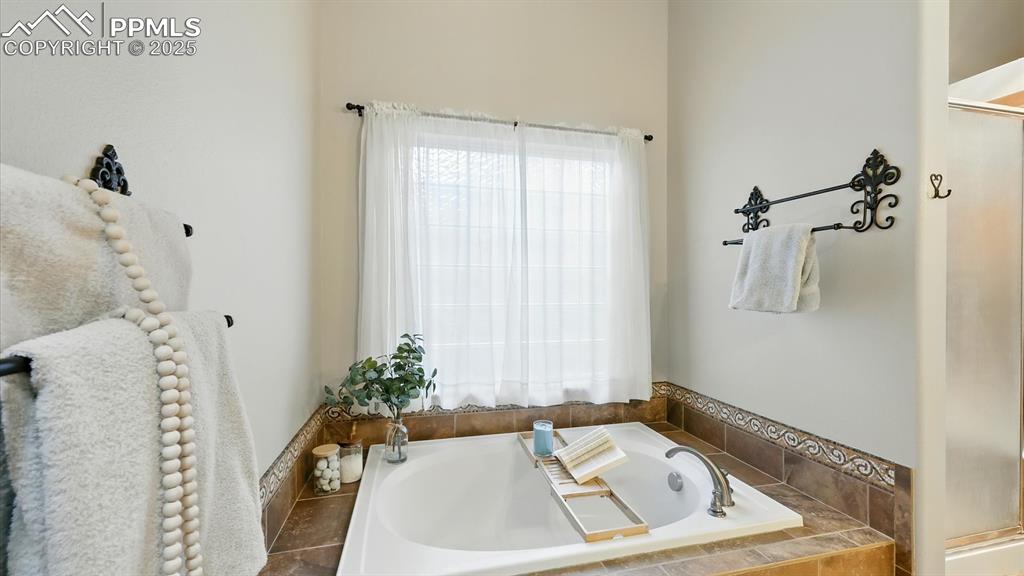Image 11 of 50: Deep soaking tub with tiled surround in Primary Bathroom.