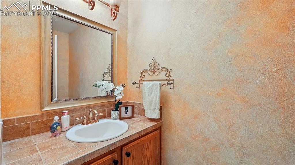 Image 28 of 50: Convenient main level Powder Bathroom with vanity and framed mirror.