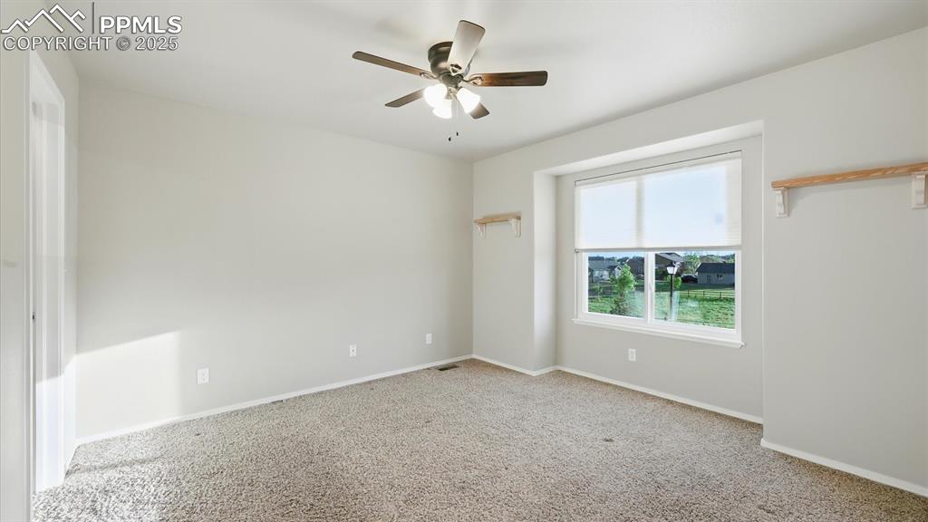 Image 39 of 50: Upper Level Bedroom #3 has neutral carpet, a lighted ceiling fan, generous 