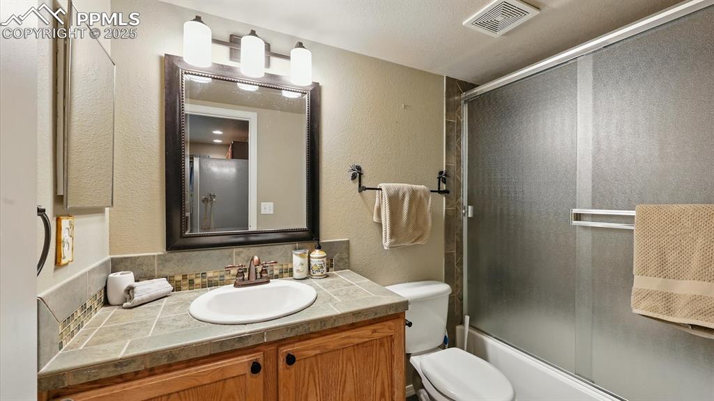 Image 43 of 50: Basement Full Bathroom with vanity, framed mirror, and enclosed tub/shower.