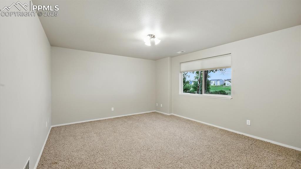 Image 44 of 50: Spacious Basement Bedroom #4 with neutral carpet and lighted ceiling fan.