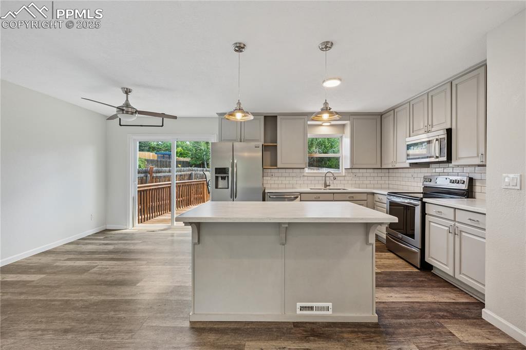 Image 16 of 35: Kitchen with appliances with stainless steel finishes, light countertops, d