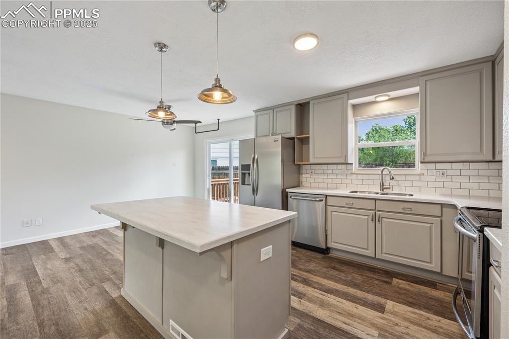 Image 17 of 35: Kitchen featuring gray cabinetry, backsplash, appliances with stainless ste