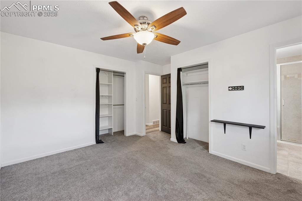 Image 21 of 35: Primary bedroom featuring two closets, light colored carpet, and ceiling fa