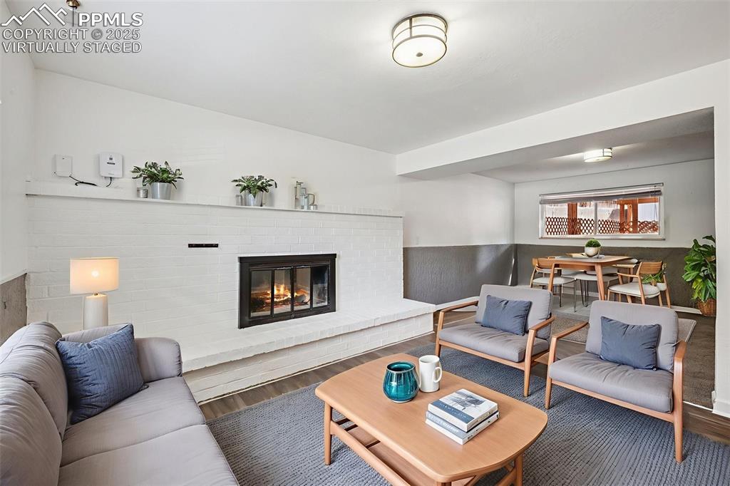 Image 30 of 35: Family room with a brick fireplace, wood finished floors, and a wainscoted 